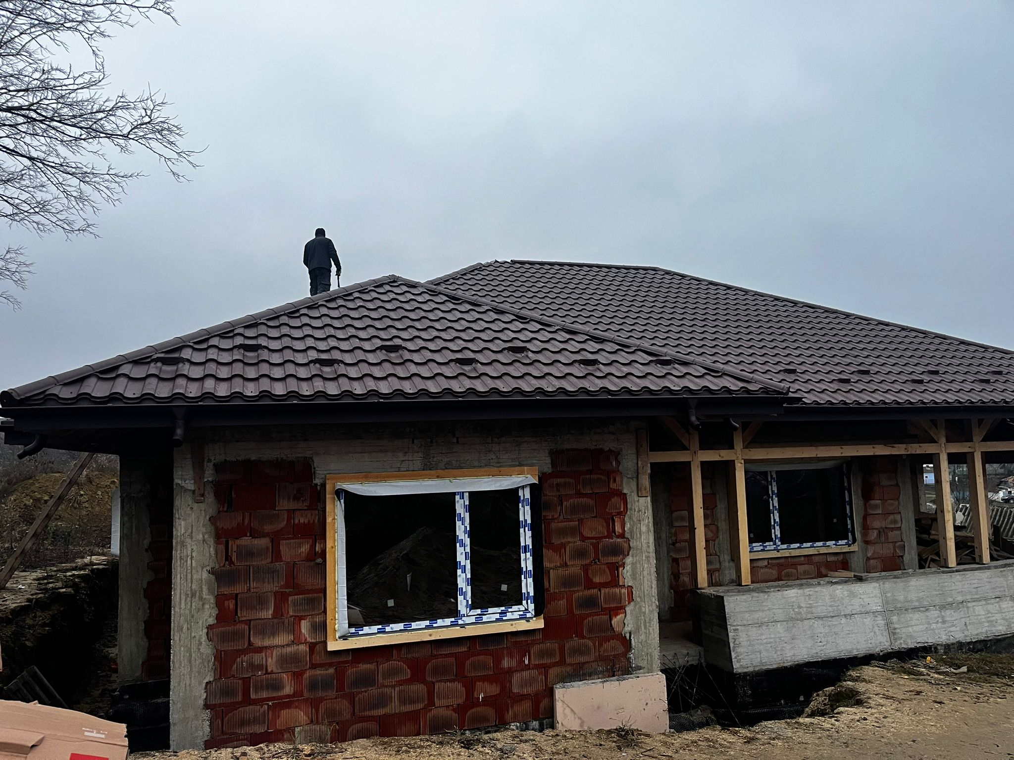 Mester pe acoperis casa in constructie cu tigla metalica maro
